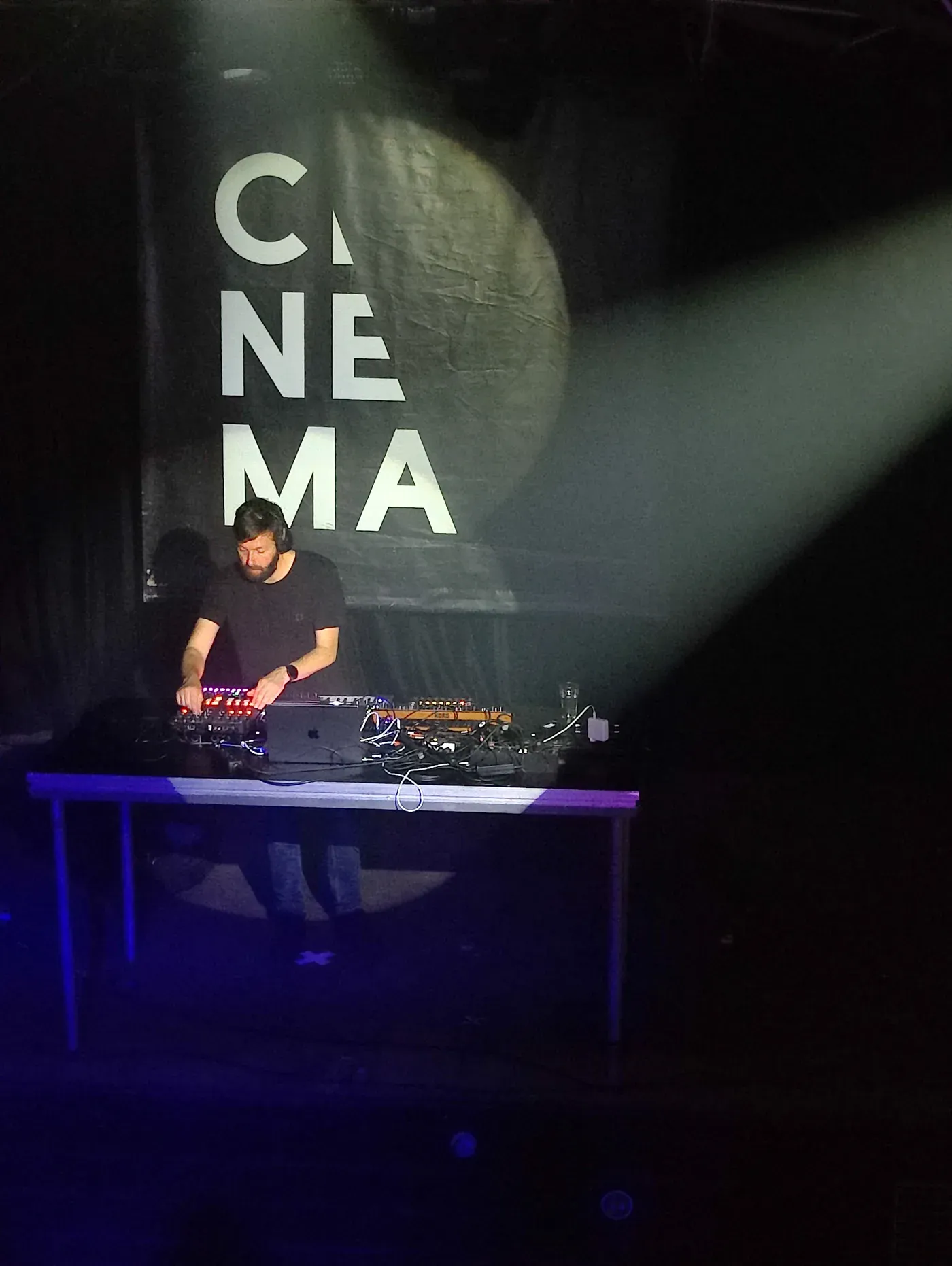 Creating Spaces performing live at Cinema, surrounded by synthesizers and controllers under stage lighting.